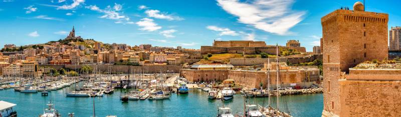 Vue panoramique du Vieux-Port de Marseille avec le Fort Saint-Jean à droite et la basilique Notre-Dame de la Garde dominant la ville.