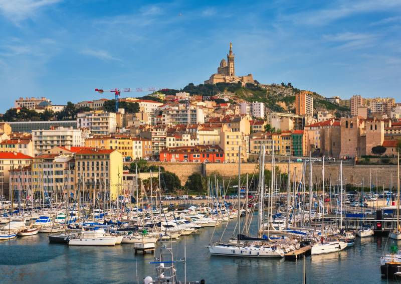 Vue sur le Vieux-Port de Marseille avec ses nombreux bateaux et la basilique Notre-Dame de la Garde en arrière-plan.
